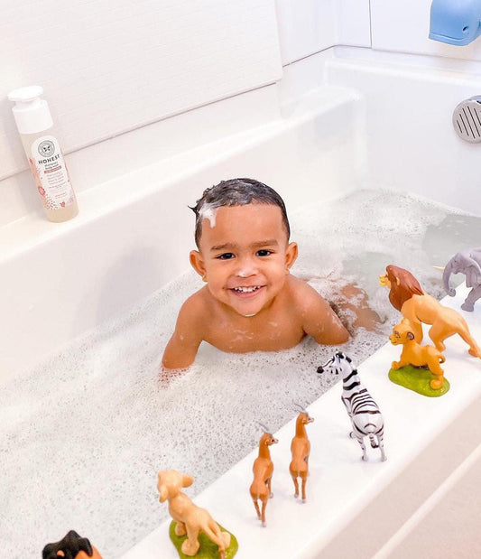 Baby in bathtub with toys and Honest shampoo + body wash