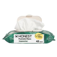 A pack of Honest Flushable Wipes with a green and white leaf-patterned wrapper, a beige flip-top lid, and a white wipe pulled out from the top. The package shows 'HONEST Flushable Wipes', 'Fragrance Free', and '42 wipes'.