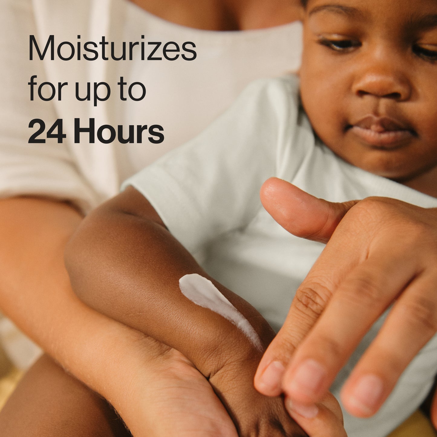 Person applying a moisturizing cream to a child's arm with text 'Moisturizes for up to 24 Hours'.