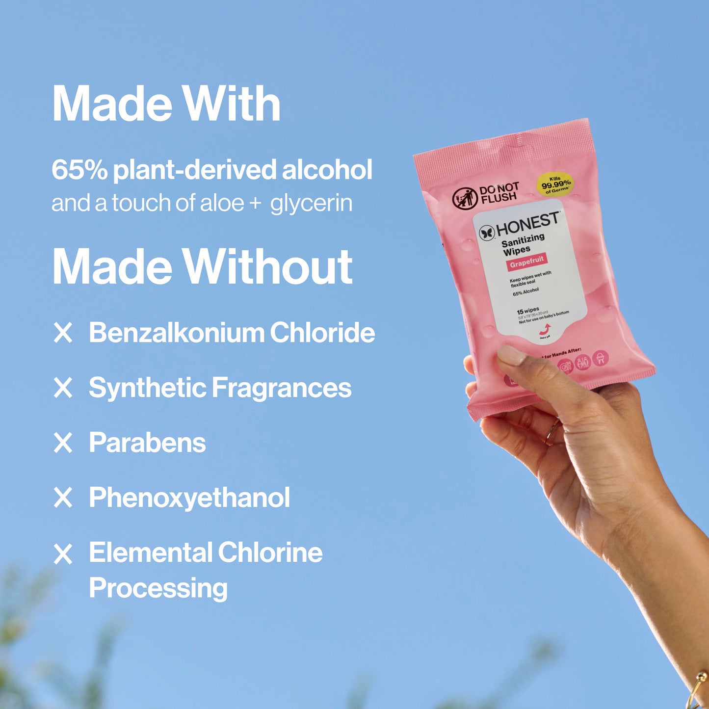 A hand holds a pink packet of Honest Aesthetics Sensing Wipes against a blue sky background, with white text on the left detailing ingredients and exclusions.