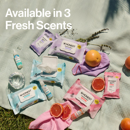 Honest brand products including wipes and bottles on a grassy background with oranges and lavender.
