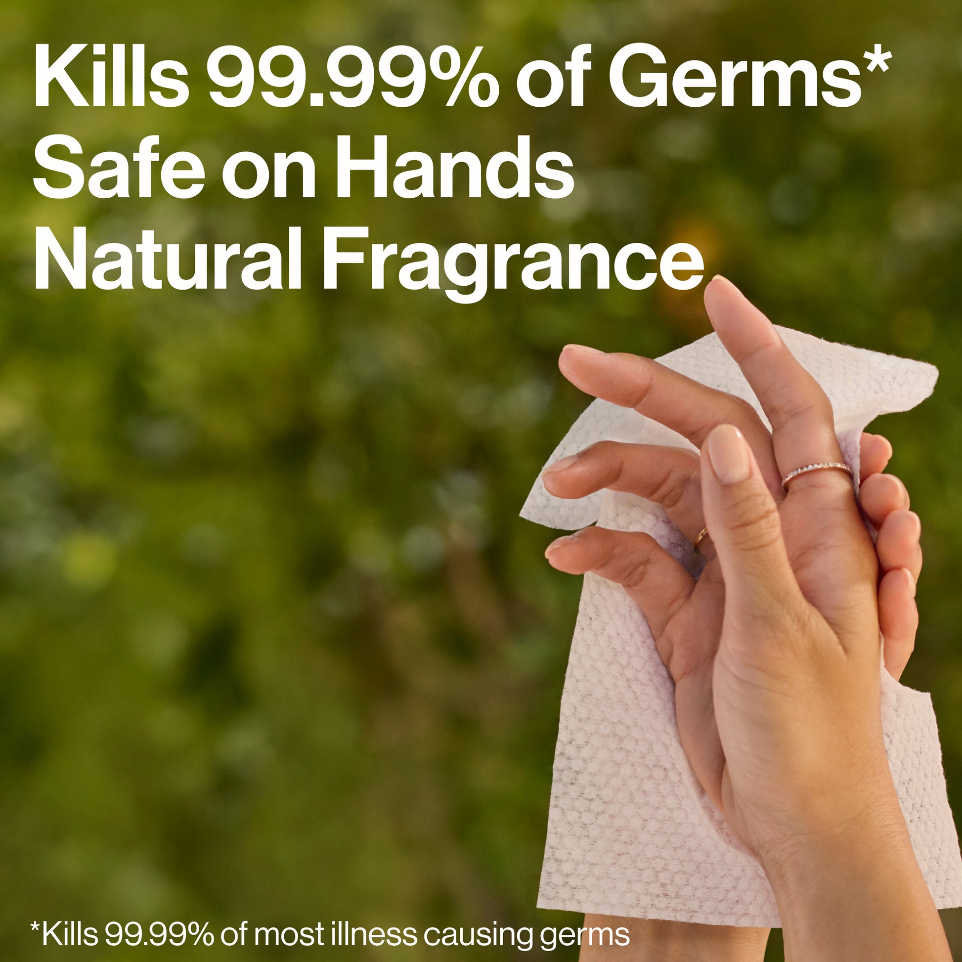 A person wipes their hands with a paper towel outdoors against a blurred green background, with large white text reading 'Kills 99.99% of Germs Safe on Hands Natural Fragrance' and a smaller disclaimer at the bottom.