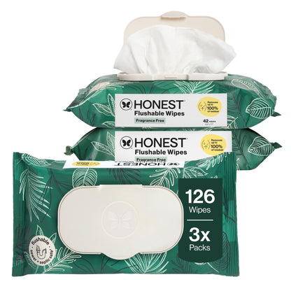 Three packs of Honest Flushable Wipes stacked together on a white background, with the top pack open to show white wipes protruding. The packs are green with white leaf patterns and a white label area that reads 'HONEST Flushable Wipes' and 'Fragrance Free'.